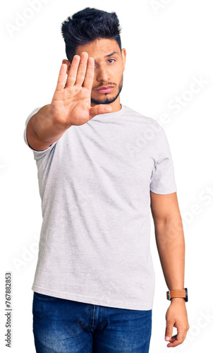 Handsome latin american young man wearing casual tshirt doing stop sing with palm of the hand. warning expression with negative and serious gesture on the face.