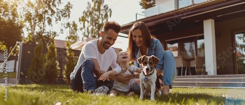 A handsome father, mother, and son enjoy time together in the backyard of an idyllic suburban home as they pet and play with their loyal Fox Terrier Retriever. The sun shines on a loving family with photo