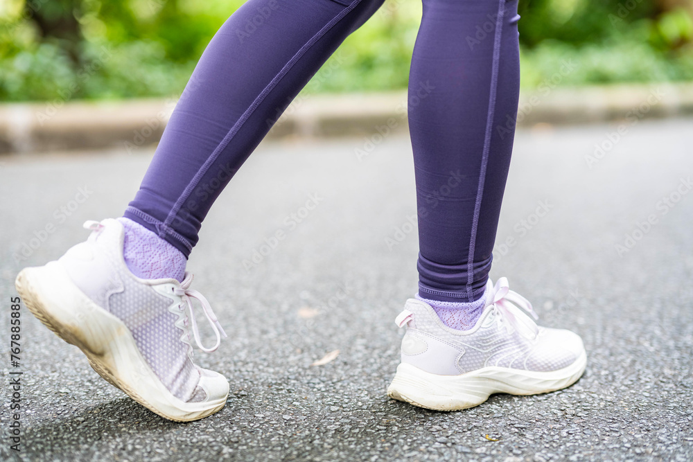 Close-up of legs and feet of woman walking in park