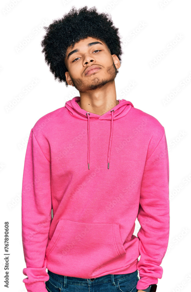 Young african american man with afro hair wearing casual pink sweatshirt relaxed with serious expression on face. simple and natural looking at the camera. Young african american man with afro hair wearing casual pink sweatshirt relaxed with serious expression on face. simple and natural looking at the camera.
