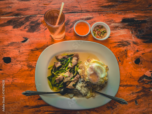 Crispy pork fried rice with fried egg served with tea and chili paste.