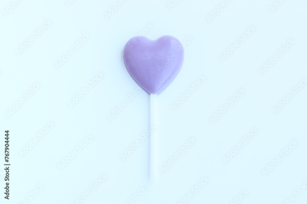 Purple heart shaped lollipop on blue background, Chocolate candy