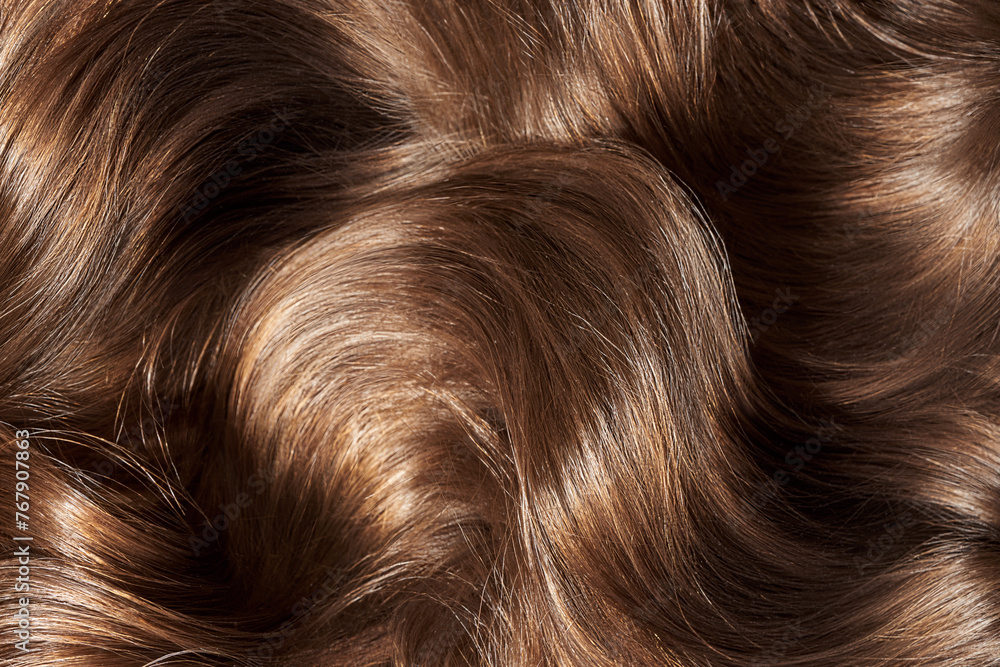 Brown hair background. Women's long brown hair. Beautifully styled wavy shiny curls.