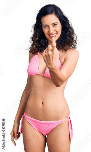 Young beautiful hispanic woman wearing bikini beckoning come here gesture with hand inviting welcoming happy and smiling