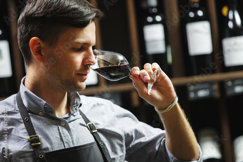 Bokal of red wine on background, male sommelier appreciating drink