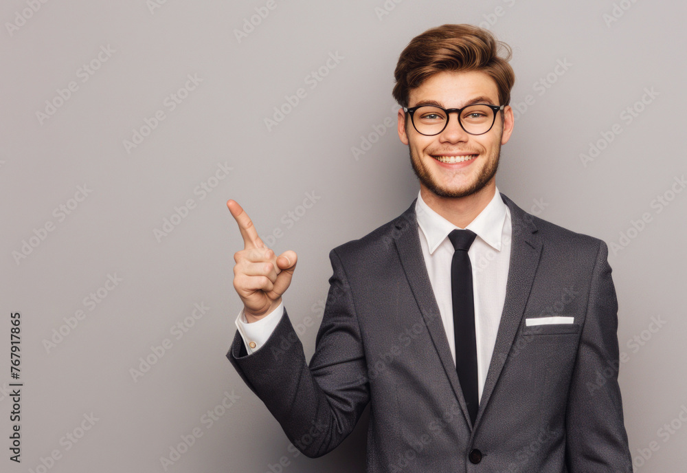 
Smiling businessman in suit pointing to the side on grey, perfect for showcasing ads. Space for your message