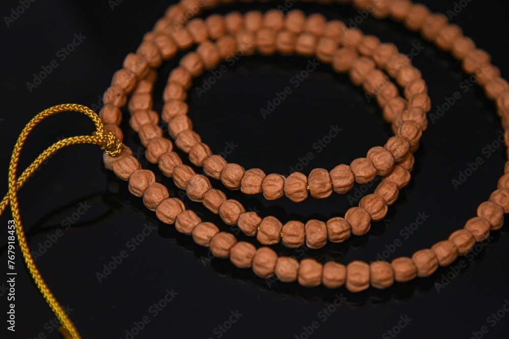 Fototapeta premium Overhead closeup of bodhi prayer beads with a golden string on a black table