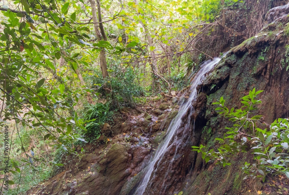 Breathtaking view of a scenic hiking trail with a waterfall cascading over the edge of a rocky cliff Breathtaking view of a scenic hiking trail with a waterfall cascading over the edge of a rocky cliff