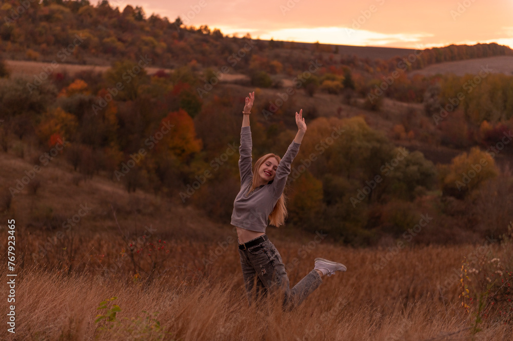Fototapeta premium Young attractive blonde woman standing on the hill at sunset 