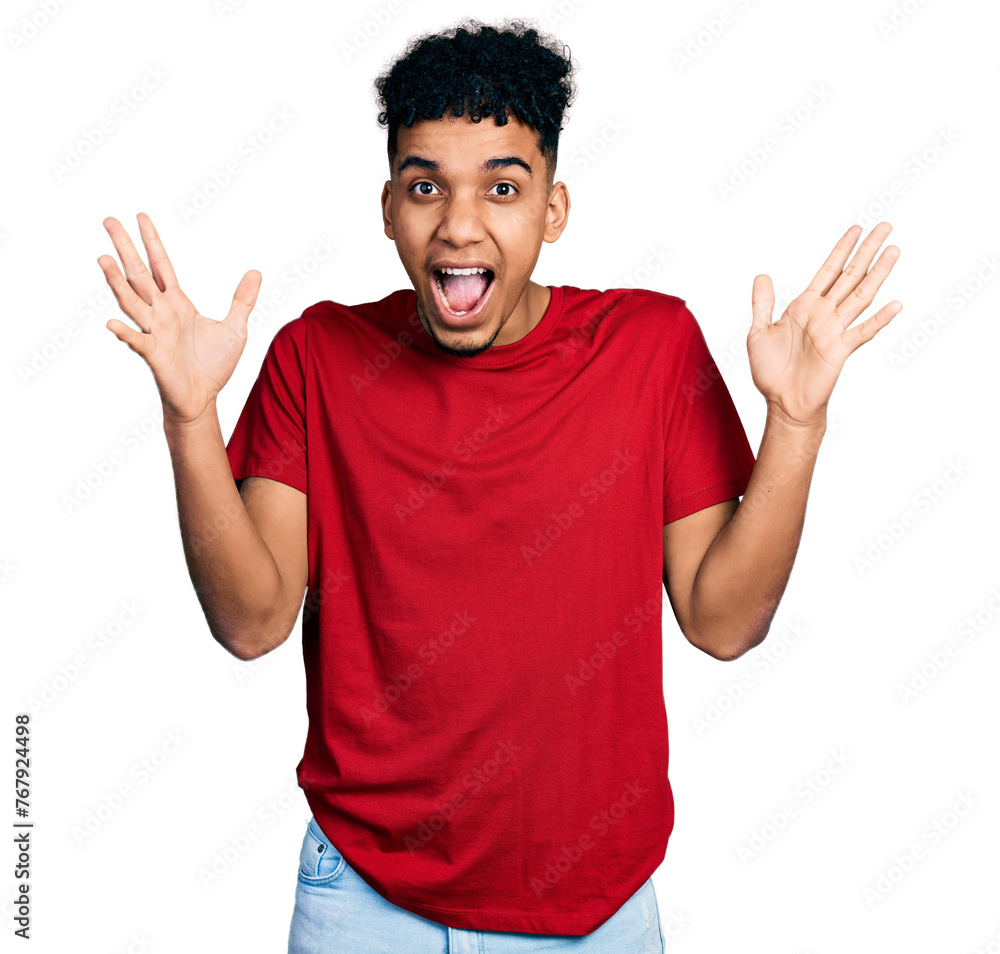 Young african american man wearing casual red t shirt celebrating crazy and amazed for success with arms raised and open eyes screaming excited. winner concept Young african american man wearing casual red t shirt celebrating crazy and amazed for success with arms raised and open eyes screaming excited. winner concept