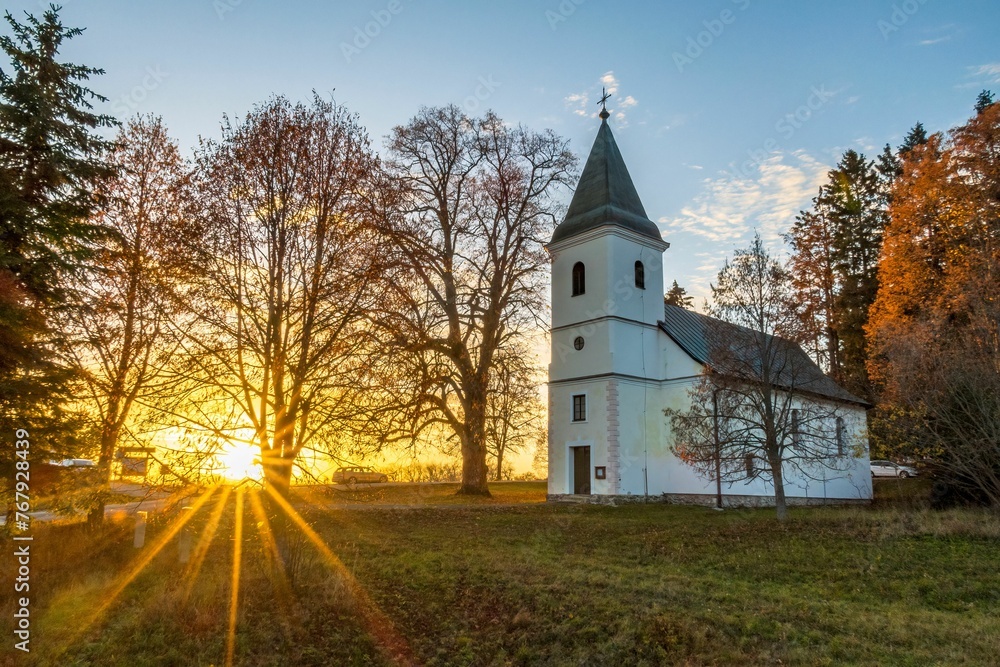Picturesque church at sunset surrounded by lush trees. Banska Bystrica, Slovakia.