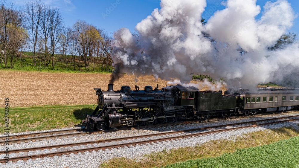 Obraz premium Antique Steam Passenger Train Traveling Thru Farmlands, With Crops Planted, Blowing Smoke