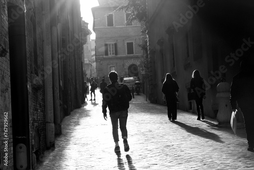Student walks alone through a quiet street in Macerata, Italy during the morning light, capturing the essence of solitude and urban life