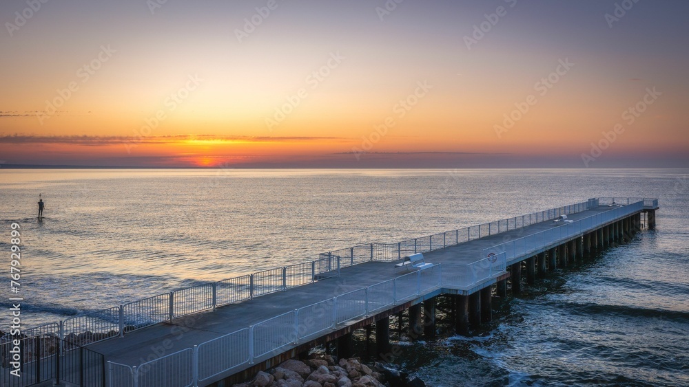 Scenic view of a pier on the sea at golden sunset