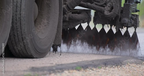 Machine making bitumen emulsion on asphalt, construction site, closeup shot photo