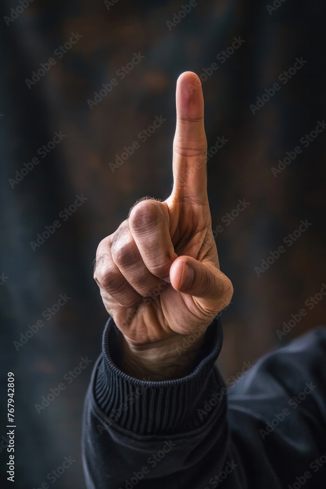 Close-up of a man's hand raising his index finger up, background image. Copy space. Blurred street background, bokeh Close-up of a man's hand raising his index finger up, background image. Copy space. Blurred street background, bokeh