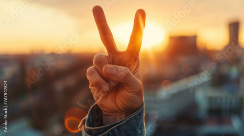 Close-up of a man's hand raising two fingers up, symbol of victory, background image. Copy space. Blurred street background, bokeh photo
