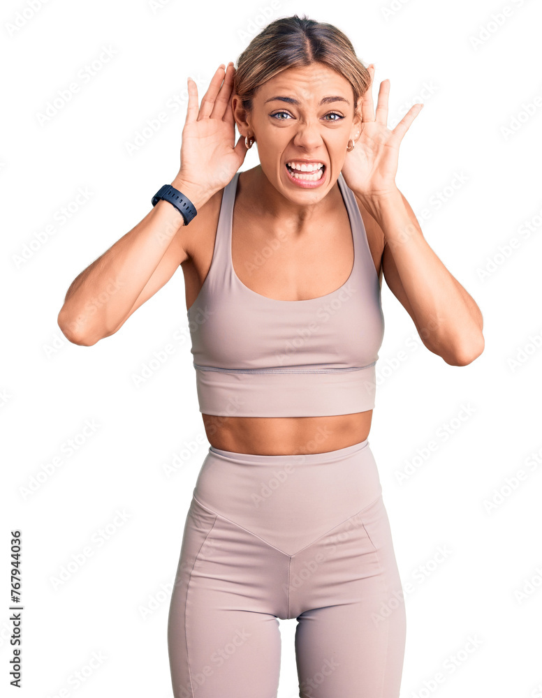 Beautiful caucasian woman wearing sportswear trying to hear both hands on ear gesture, curious for gossip. hearing problem, deaf Beautiful caucasian woman wearing sportswear trying to hear both hands on ear gesture, curious for gossip. hearing problem, deaf