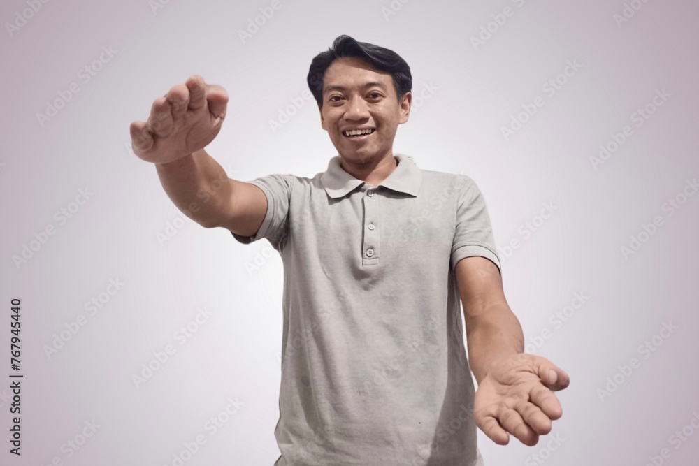 Handsome happy Asian man showing something with his palms in front, man holding something with both hands. Indonesian man holding something in his palm to insert an advertisement. Copy space image. Handsome happy Asian man showing something with his palms in front, man holding something with both hands. Indonesian man holding something in his palm to insert an advertisement. Copy space image.