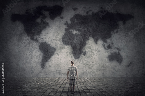 Person stands in front of a concrete wall looking at the world map. Travel limitations concept