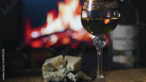 Still life of glass of wine apples and cheese in front of burning fireplace. photo