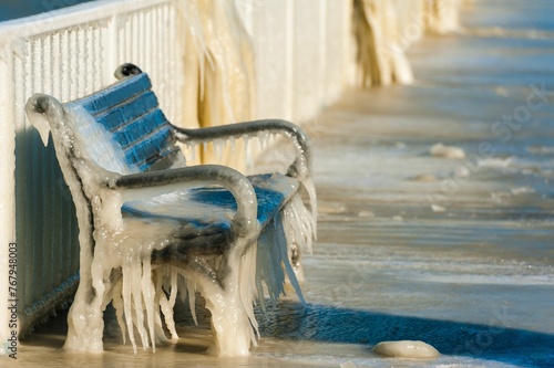 Wooden bench situated on a boardwalk, surrounded by frosty winter icicles
