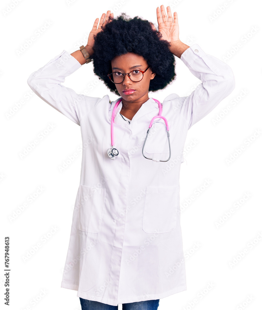 Young african american woman wearing doctor coat and stethoscope doing bunny ears gesture with hands palms looking cynical and skeptical. easter rabbit concept. Young african american woman wearing doctor coat and stethoscope doing bunny ears gesture with hands palms looking cynical and skeptical. easter rabbit concept.