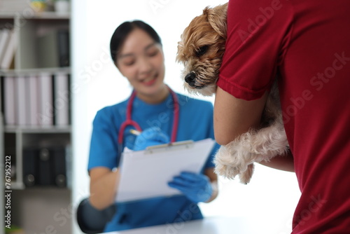 Dog owner brings sick dog to veterinarian's office for treatment. Female veterinarian is examining a dog's health in the veterinarian's office.