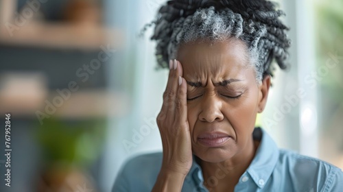 A middle aged woman having a severe headache photo
