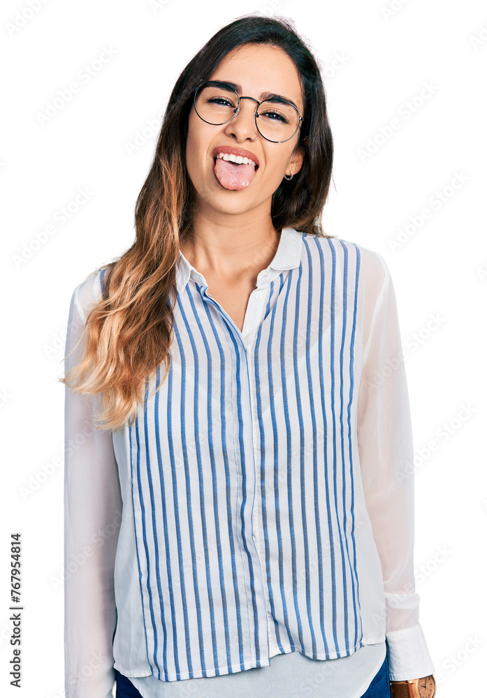 Beautiful hispanic woman wearing casual striped shirt sticking tongue out happy with funny expression. emotion concept. Beautiful hispanic woman wearing casual striped shirt sticking tongue out happy with funny expression. emotion concept.