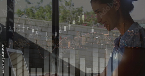 Image of financial data processing over caucasian businesswoman using laptop and cityscape