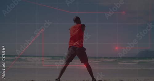 Image of red light trails over rear view of african american fit man stretching at the beach