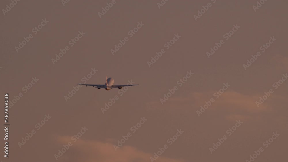 The plane is flying against the background of a reddish evening sky with clouds, gaining altitude The plane is flying against the background of a reddish evening sky with clouds, gaining altitude