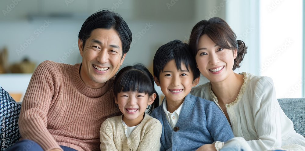 Happy Japanese family posing on the couch together at home in the living room