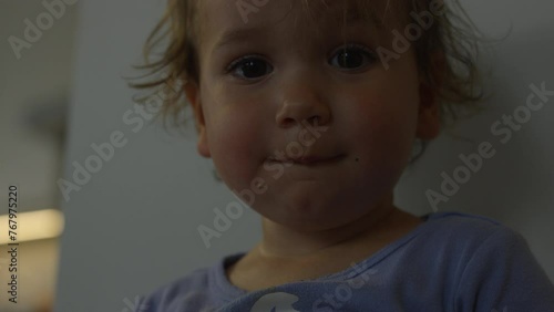 Toddler girl using potty looks towards camera and around - close up on face photo