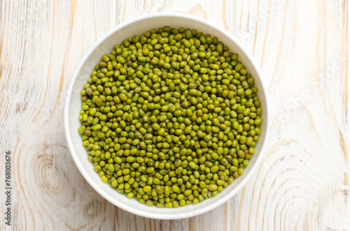 Green mung beans in a ceramic bowl on a white wooden background. Organic legumes. Vegan and vegetarian food. The concept of healthy eating. Horizontal orientation. Top view. Selective focus.