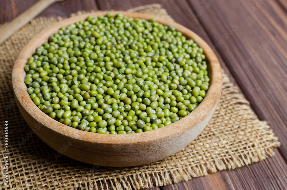 Green mung beans in a bowl on burlap on a wooden table. Organic legumes. Vegan and vegetarian food. Rustic style. The concept of healthy eating. Horizontal orientation. Copy space. Selective focus. Green mung beans in a bowl on burlap on a wooden table. Organic legumes. Vegan and vegetarian food. Rustic style. The concept of healthy eating. Horizontal orientation. Copy space. Selective focus.