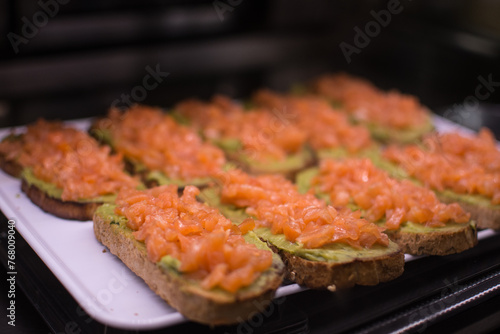 a tray of food with salmon on it and avocado on the bottom