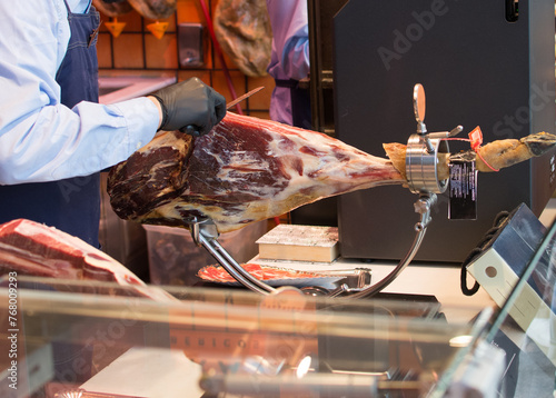 a man is cutting a piece of Iberian Ham with a knife