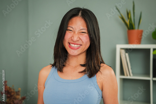 Close up individual portrait of asian young woman smiling and looking at camera with perfect white teeth standing at home linving room. One friendly happy chinese female with confident expression photo