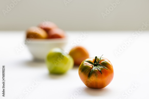 Fresh daejeo tomato in a white bowl under warm sunlight indoor natural light on white background photo