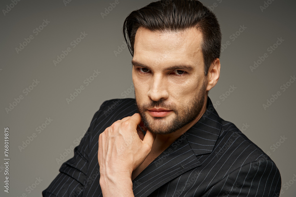handsome man with bristle in his 30s posing in elegant pinstripe suit and looking at camera handsome man with bristle in his 30s posing in elegant pinstripe suit and looking at camera