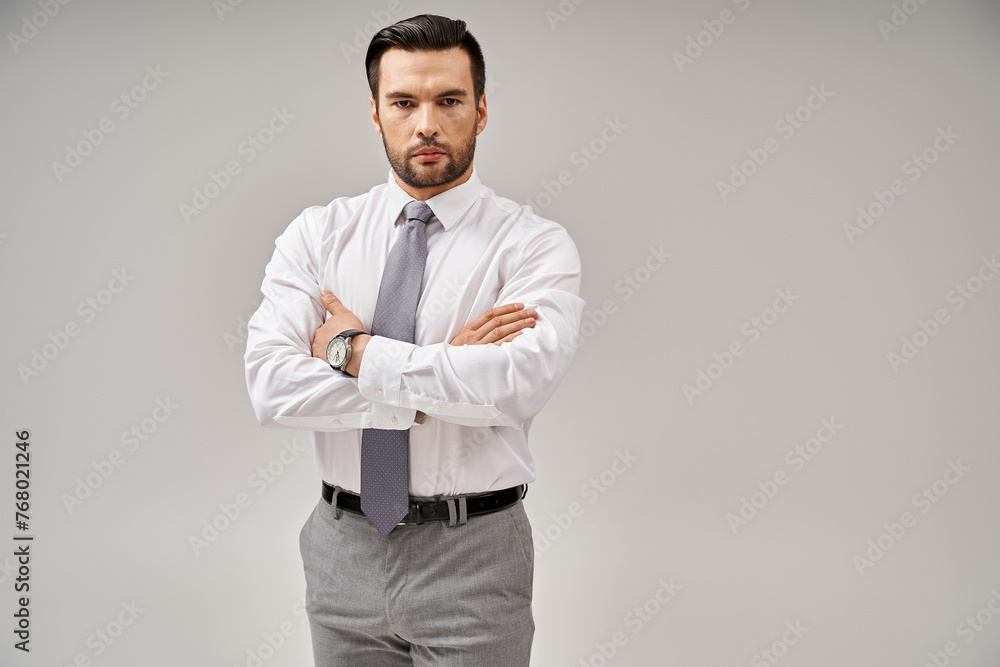 portrait of businessman in suit standing with crossed arms while posing on grey background portrait of businessman in suit standing with crossed arms while posing on grey background