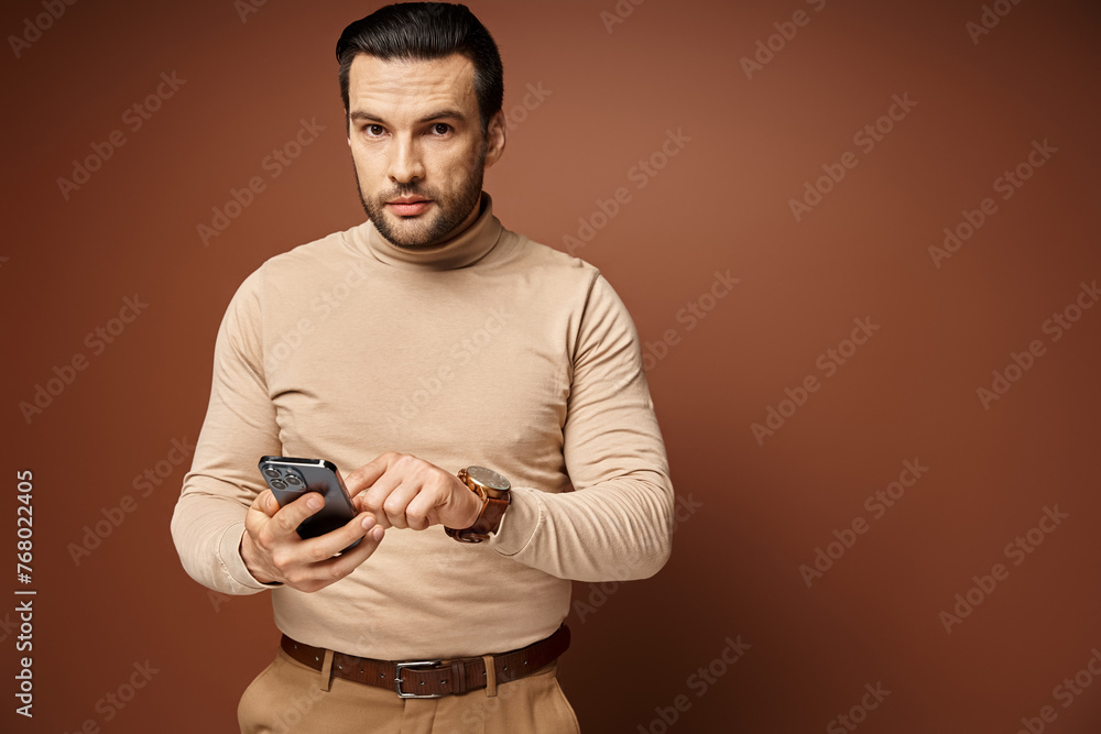 good looking man with bristle in turtleneck using his smartphone on beige background, social media good looking man with bristle in turtleneck using his smartphone on beige background, social media