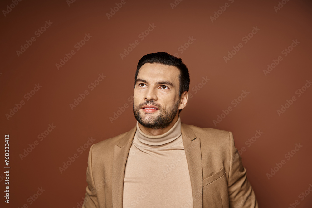 Fototapeta premium dreamy and handsome man with bristle smiling and posing in stylish beige blazer on beige backdrop