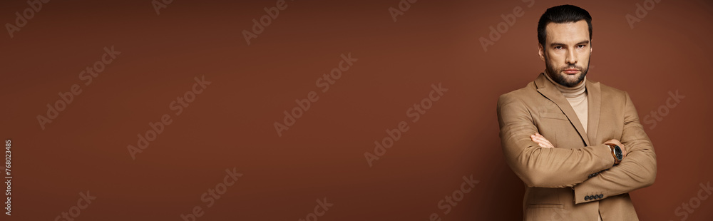 handsome man in blazer giving confident look while standing with folded arms on beige, banner handsome man in blazer giving confident look while standing with folded arms on beige, banner