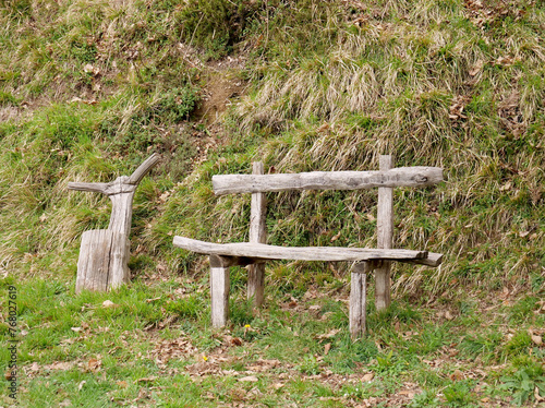 A handcrafted wooden bench and stool in a natural green area