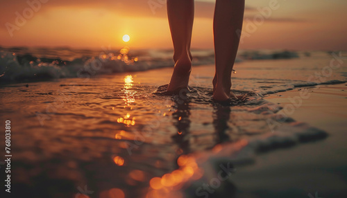 Low-angle view of a girl's feet walking on the beach at sunset