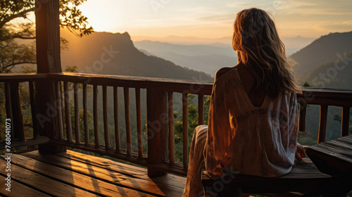 Young woman sitting on terrace and looking at sunset in the mountains © Art AI Gallery