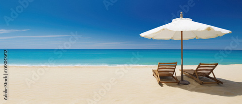 Beach chair and umbrella on the sandy beach with blue sea background.